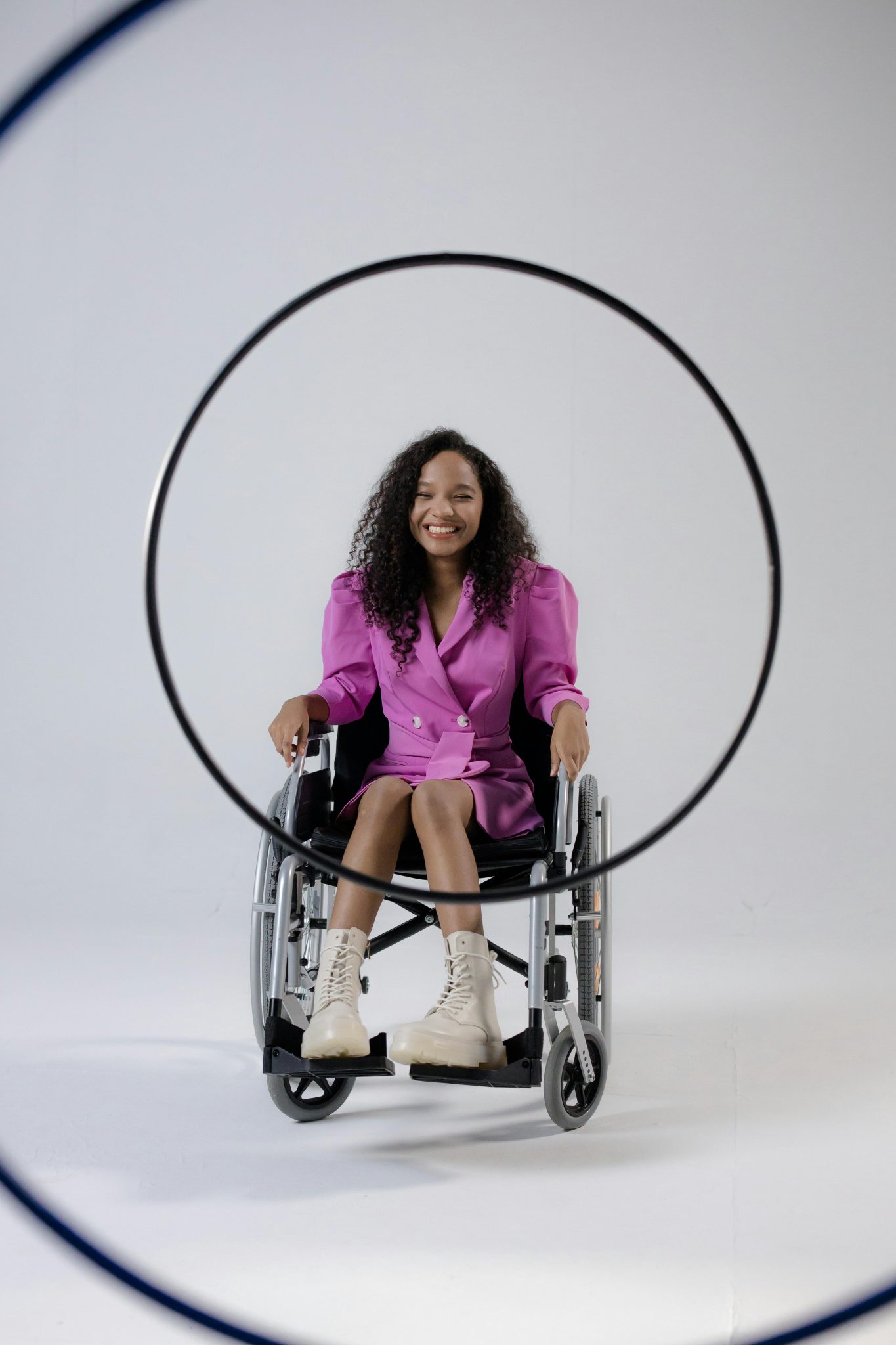 Smiling woman in a wheelchair, wearing a pink outfit, framed by a hula hoop.